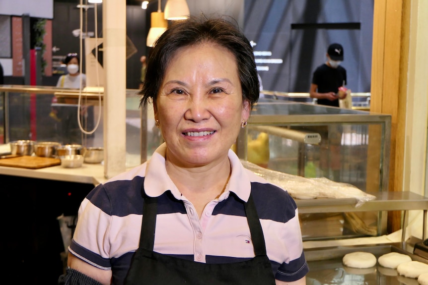 A woman stands in front of a takeaway shop.