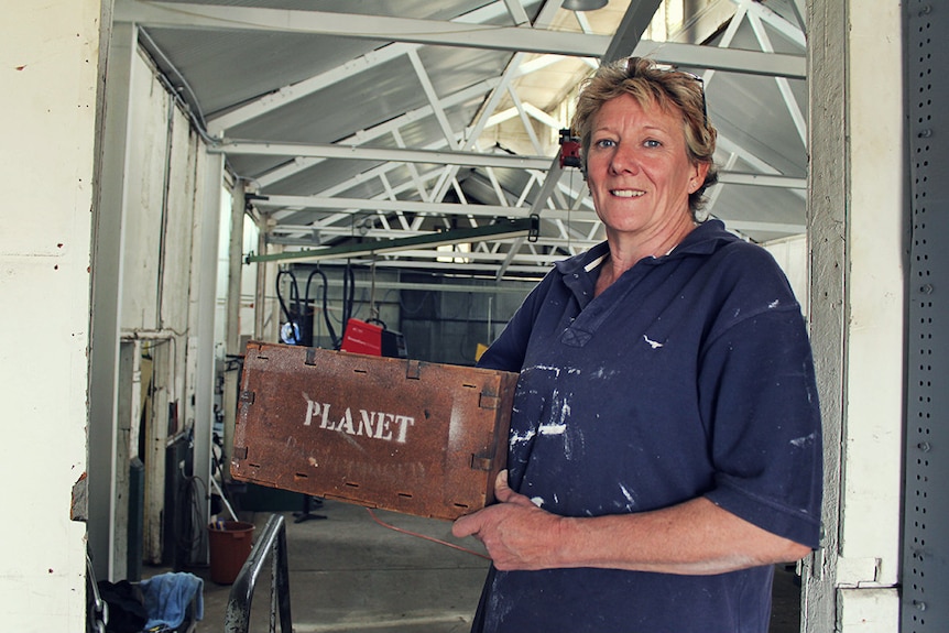 A woman holds an old box that butter was stored in in the 1900s