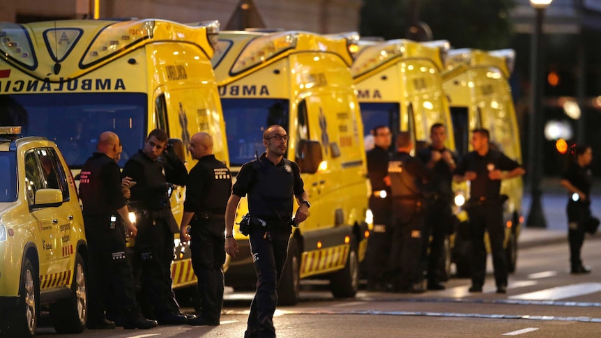 Emergency workers and stand on a blocked street next to ambulances in Barcelona.