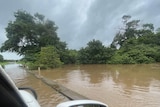 A car drives towards a bridge that has flooded over