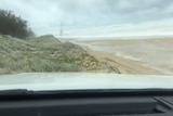 A still image from the video showing a car driving on sand dunes.