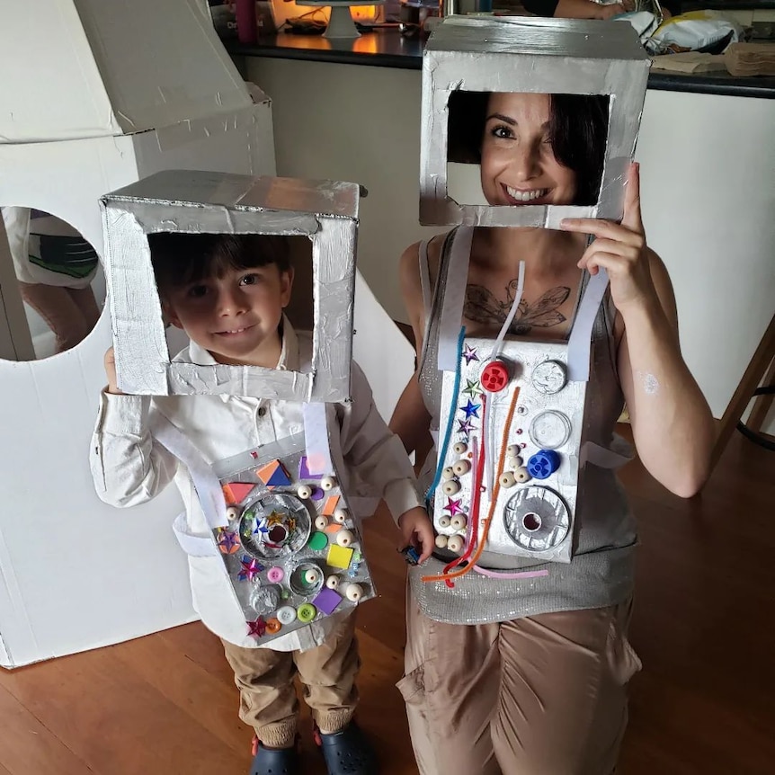 A woman with her son, both have arty-looking boxes on their heads.