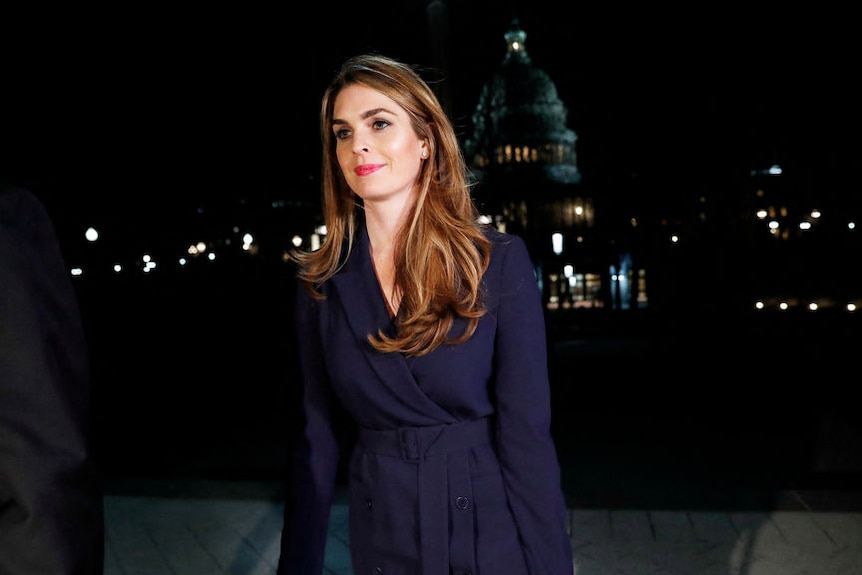 A woman in a blue dress and long brown hair at night time. The US Capitol is visible in the background.