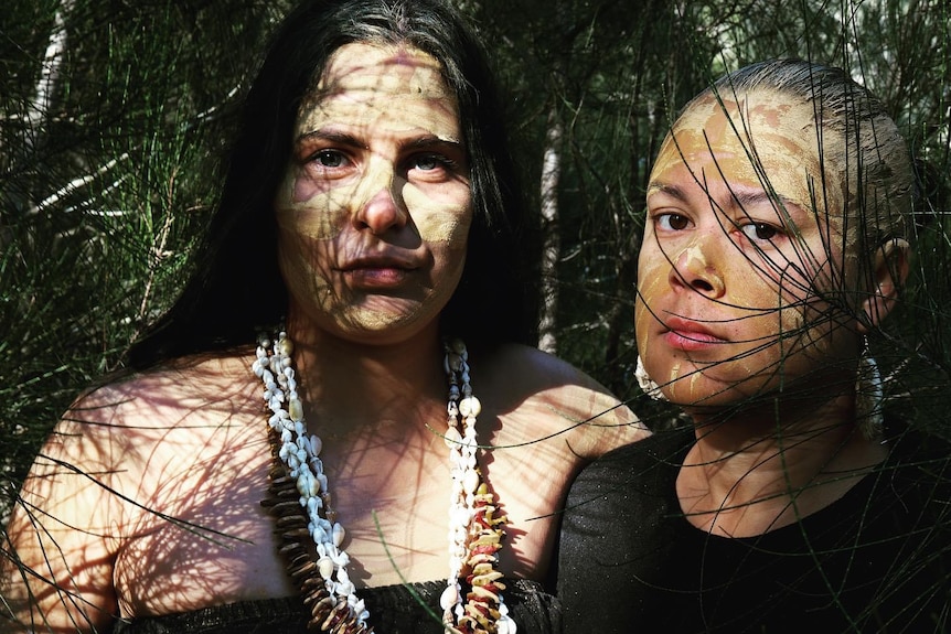 Close up of two Indigenous woman among some tree branches