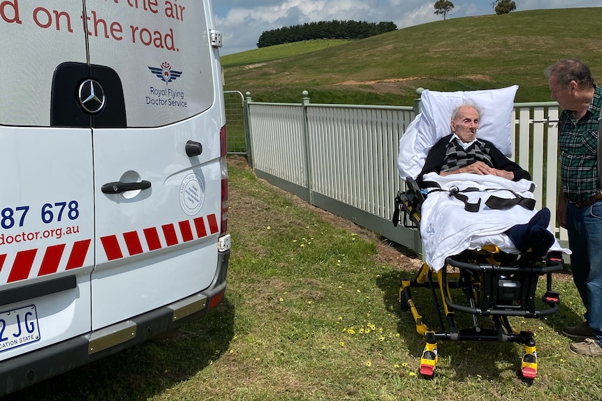 An elderly man on a stretcher, at a farm. 