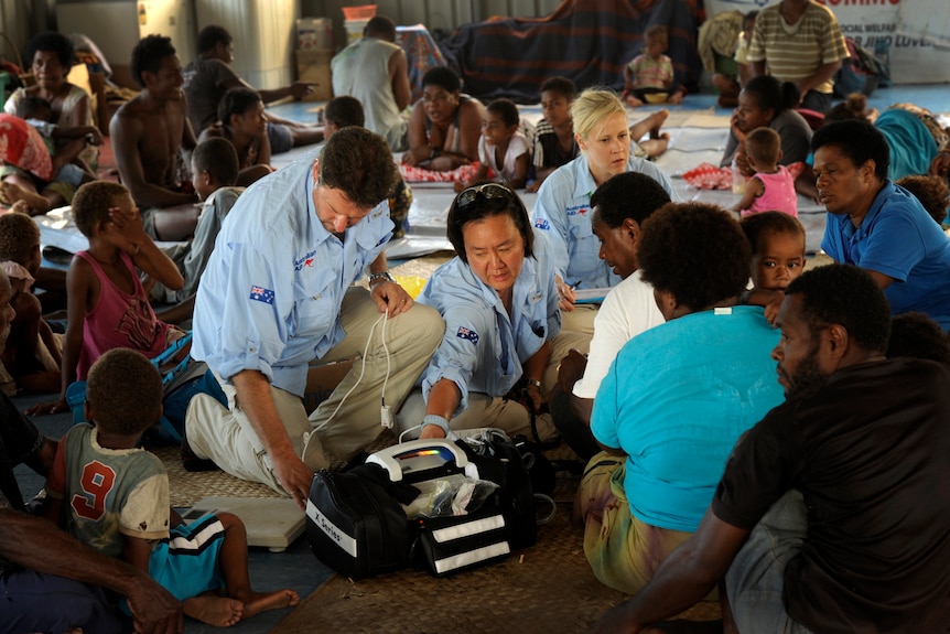 doctors in blue shirts providing aid to fijian people