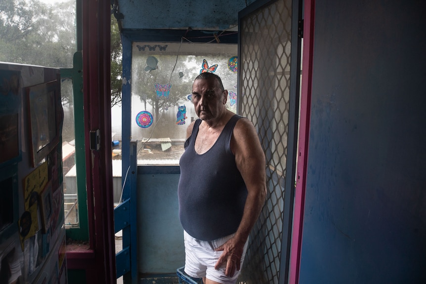 A man stands inside a veranda.