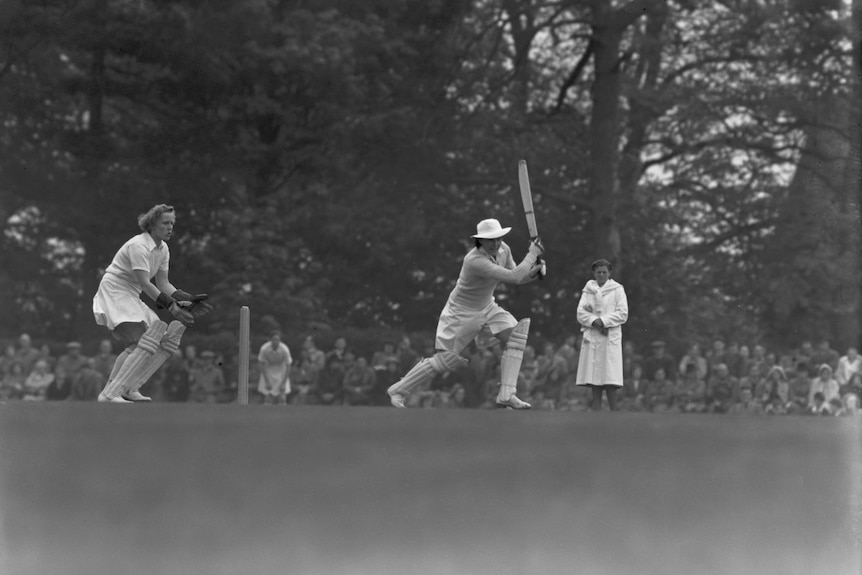 A black and white image of Betty Wilson after hitting the ball on the cricket pitch.