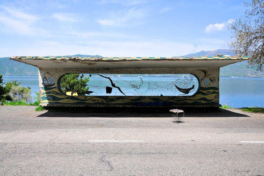 An old bus stop in front of a river