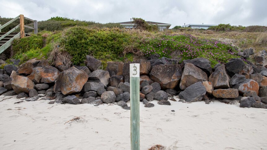 A wooden pole sticks out of the sand on a beach.
