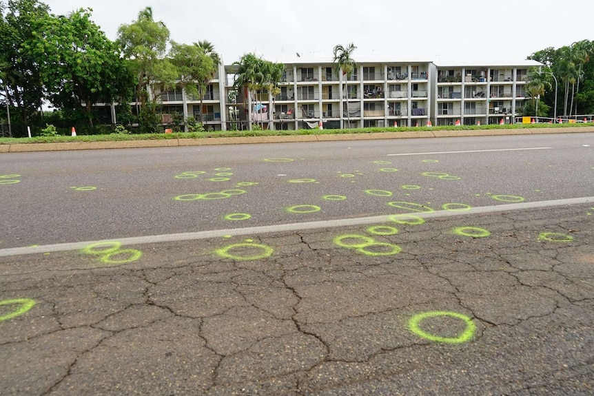 green circles are seen spray painted onto the Stuart Highway in front of building flats.