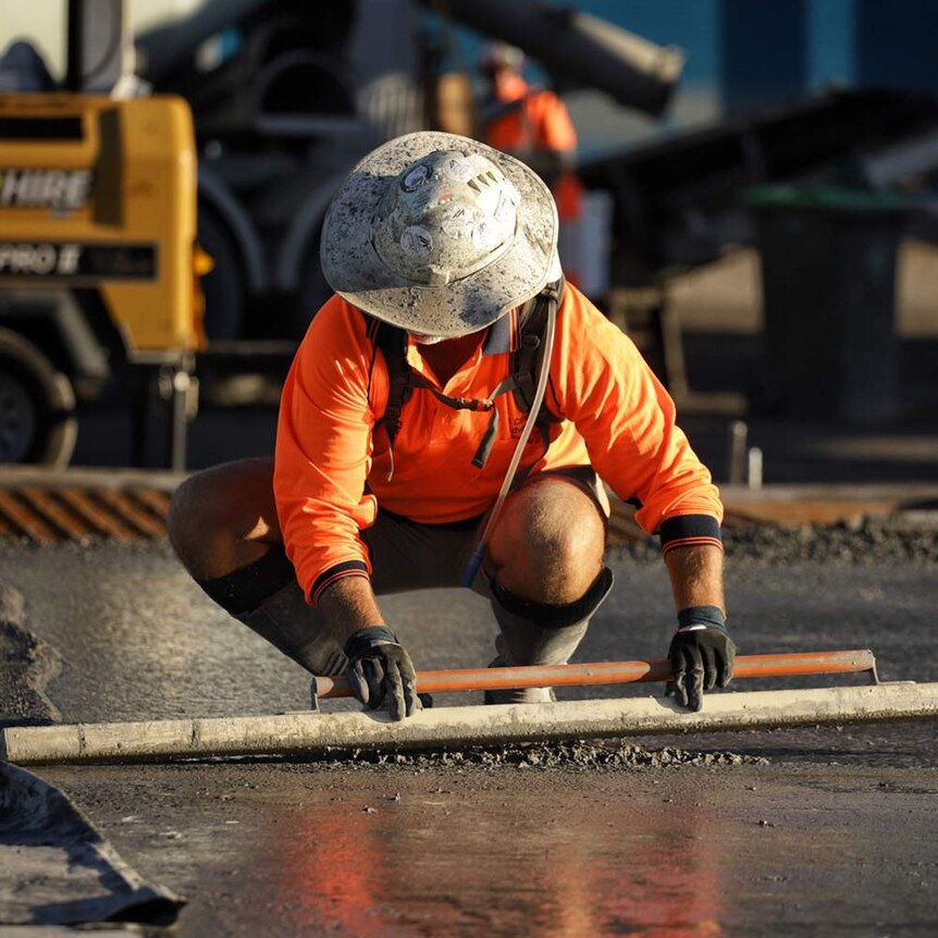 A worker smooths concrete at slab pour at building construction site at Radar Street at Lytton at Brisbane.