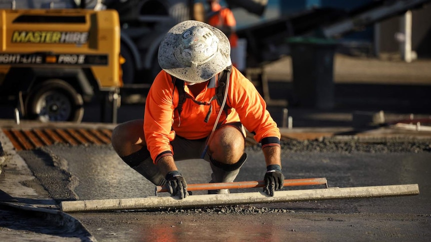 A worker smooths concrete at slab pour at building construction site at Radar Street at Lytton at Brisbane.