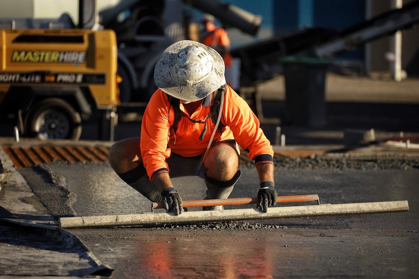 A worker smooths concrete at slab pour at building construction site at Radar Street at Lytton at Brisbane.