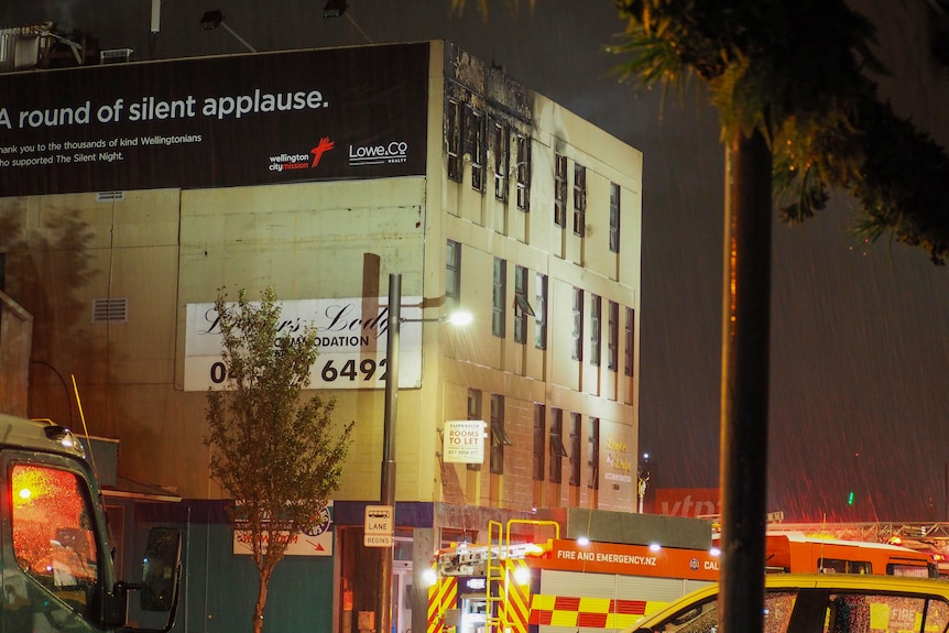 A building with visible burns, firetrucks at the bottom of the picture. 