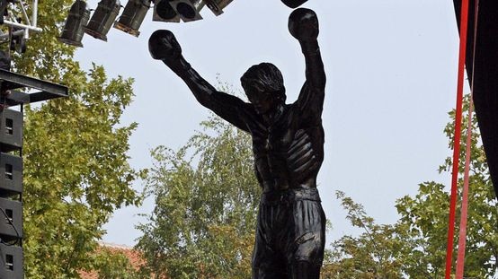 Villagers look at a statue of the film character Rocky Balboa.