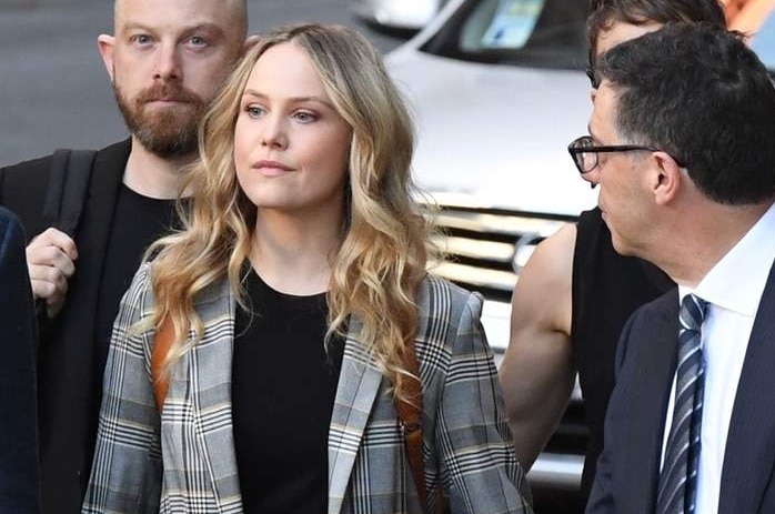 woman walks down road surrounded by business people