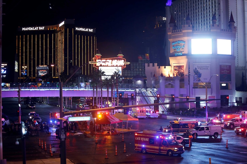 Emergency vehicles with lights on crowd a road intersection near the Mandalay Bay hotel.