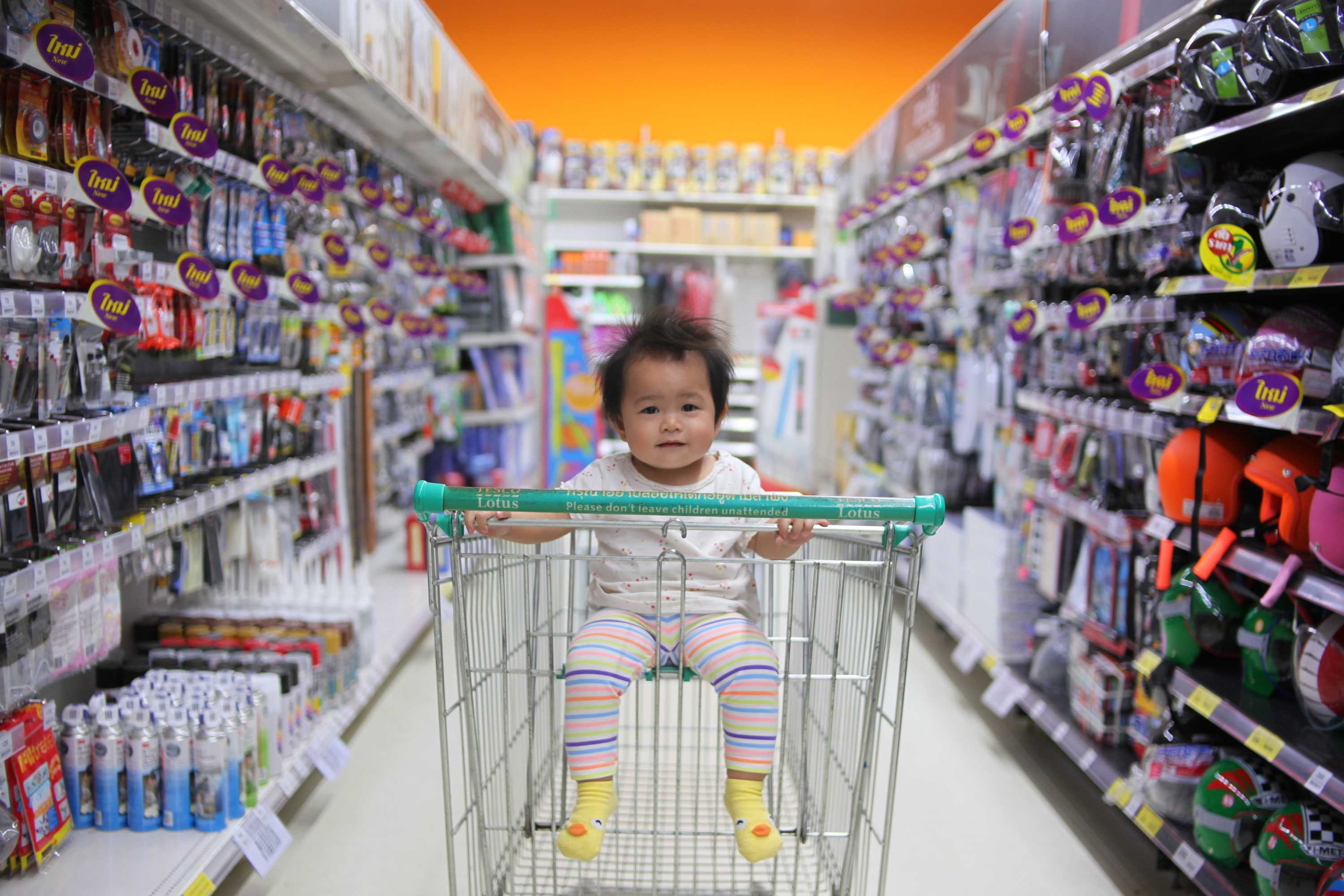 A baby rides in a trolley through a supermarket aisle to depict ways to reduce waste and be sustainable when you have children.