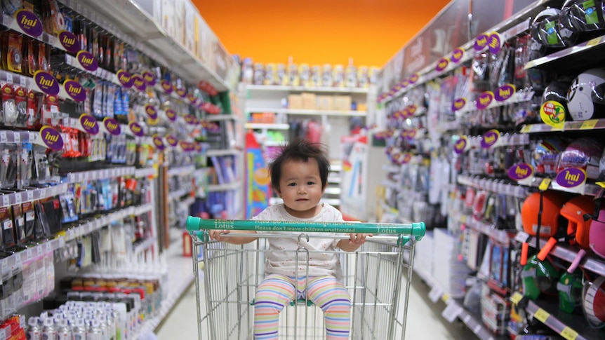 A baby rides in a trolley through a supermarket aisle to depict ways to reduce waste and be sustainable when you have children.