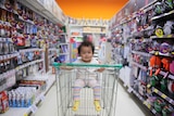 A baby rides in a trolley through a supermarket aisle to depict ways to reduce waste and be sustainable when you have children.