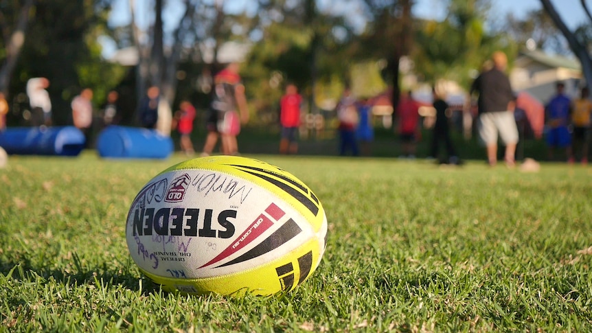 A football in the foreground. Further away a training session out of focus. 