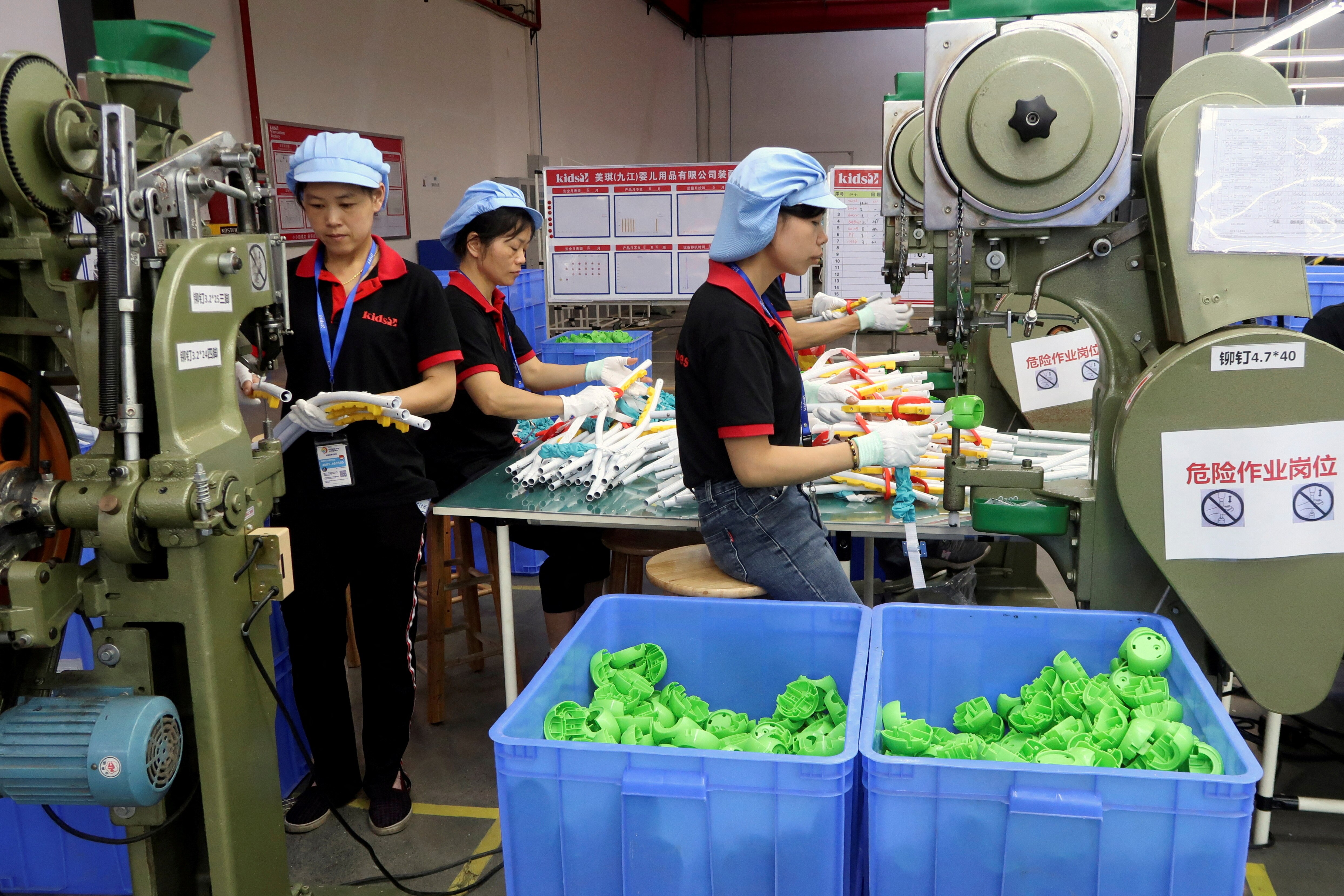 Three factory workers sort through bins or green plastic toys 