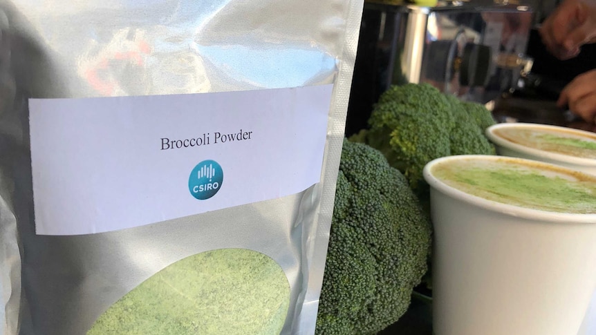 A large, shiny silver sachet with a panel showing bright green powder in front of broccoli heads and two coffees