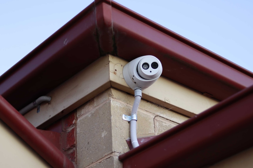 A security camera fixed to a brick home just below the gutter