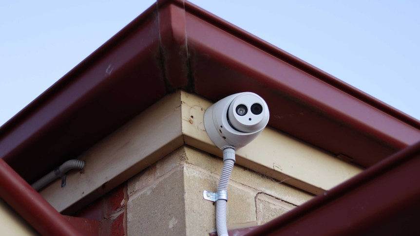 A security camera fixed to a brick home just below the gutter