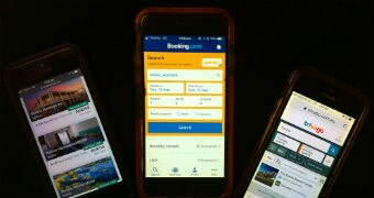 Three mobile phones showing various accommodation booking sites.