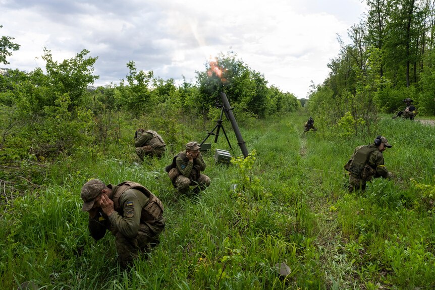 Ukrainian servicemen accompanied by members of the foreign legion fire mortars at Russian positions.