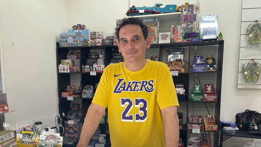 Store owner Joseph Sacco leans on a cabinet filled with trading cards