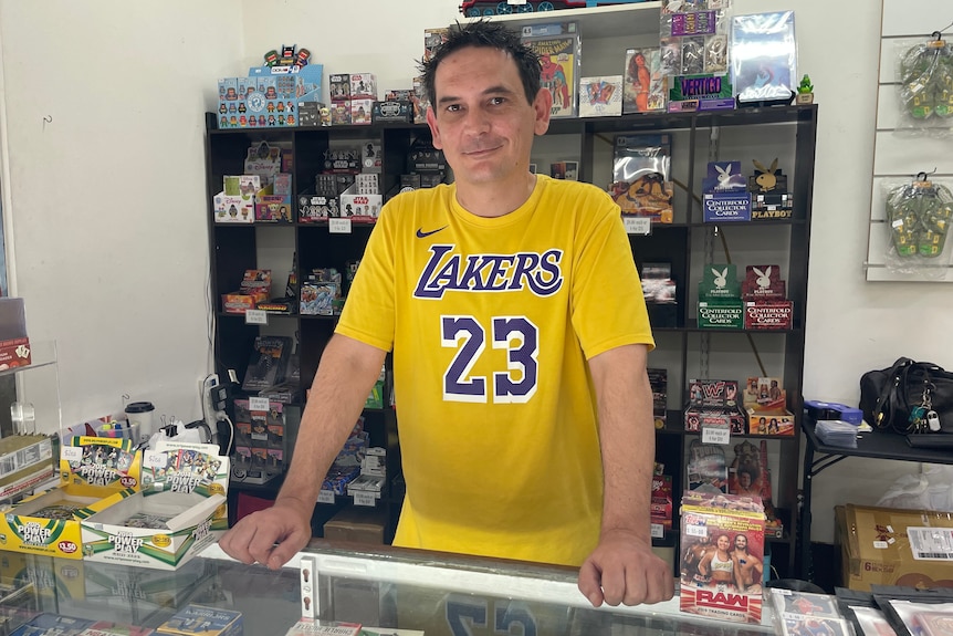 Store owner Joseph Sacco leans on a cabinet filled with trading cards