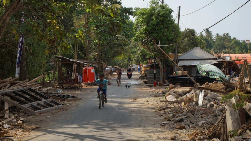 An Indonesian child rides his bike through a Lombok village reduced to rubble by a series of earthquakes in August.