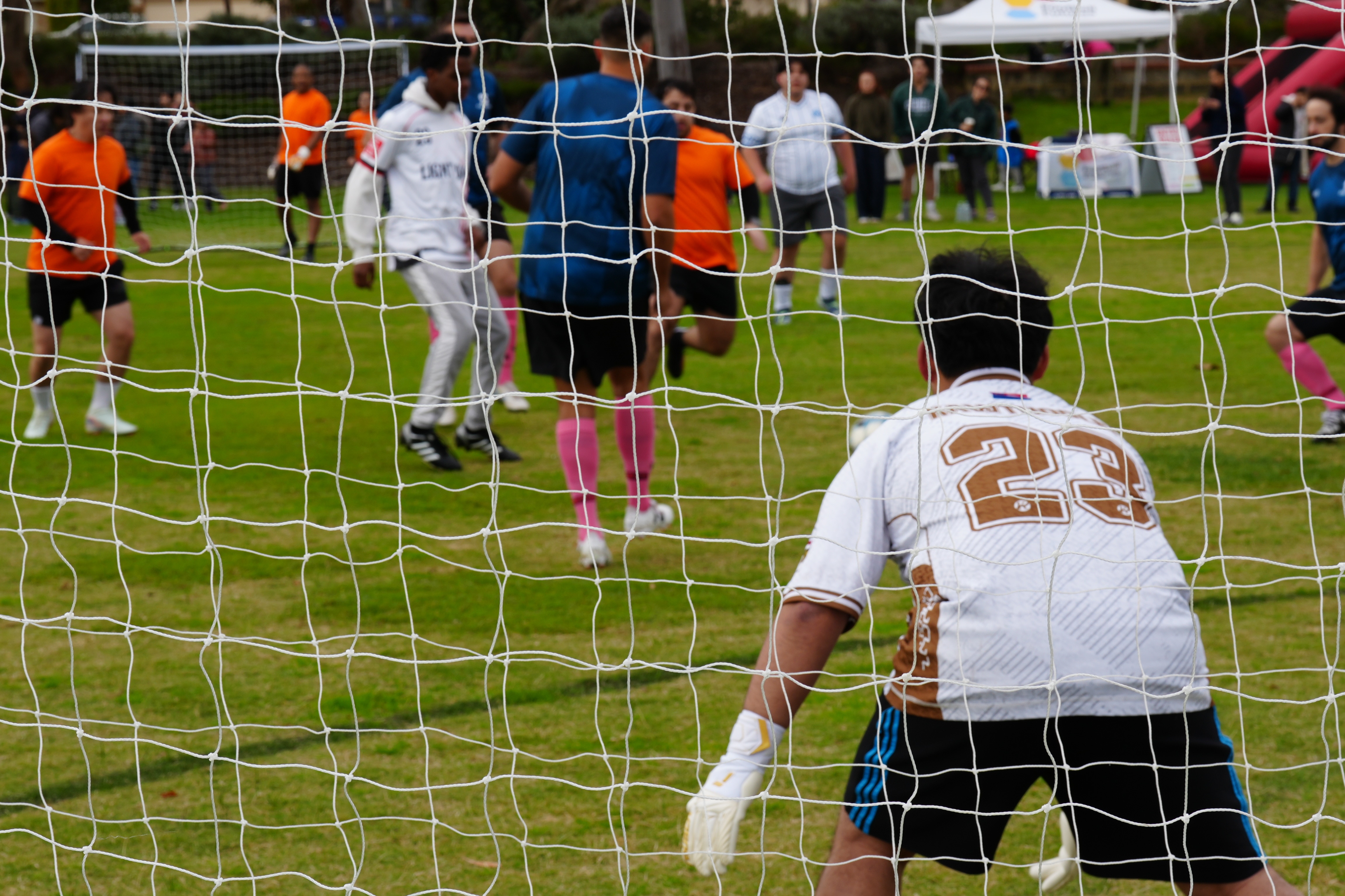 A goalie stands with his back to the camera during a soccer game.