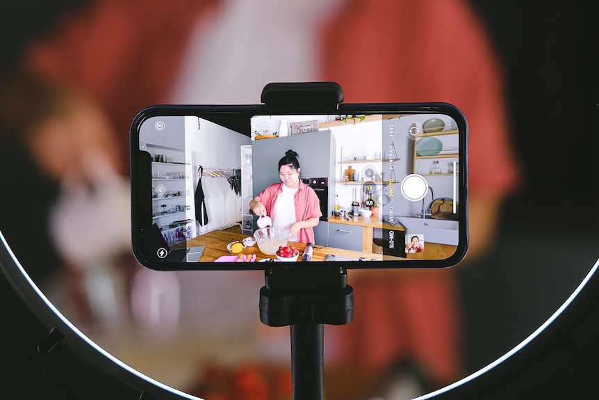 A person films themselves cooking through an iphone.