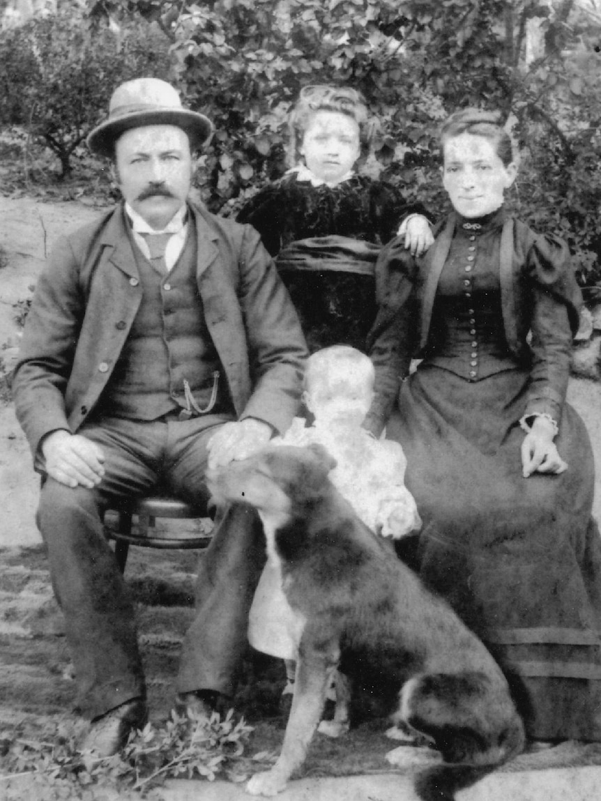 A black and white photo of a man, woman, two children and a dog from the late 1800s.