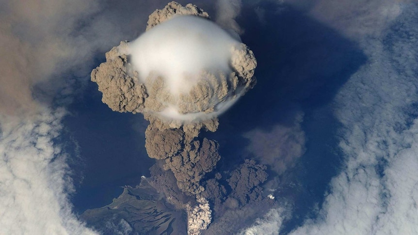 Dramatic photo from above of the Sarychev Volcano erupting, large grey clouds of ash rising above