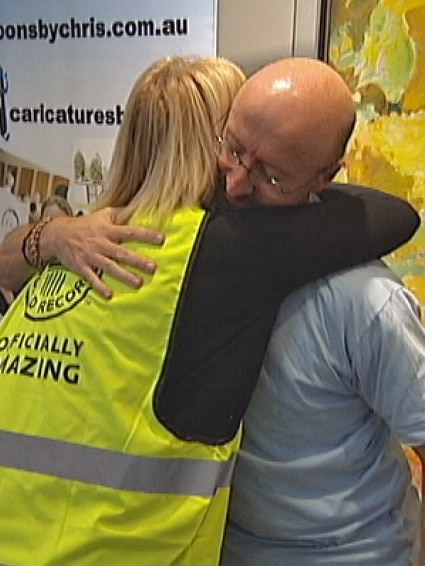 Cartoonist Chris Wilson hugs his partner to celebrate reaching the milestone 50 hours of drawing in the hospital foyer.