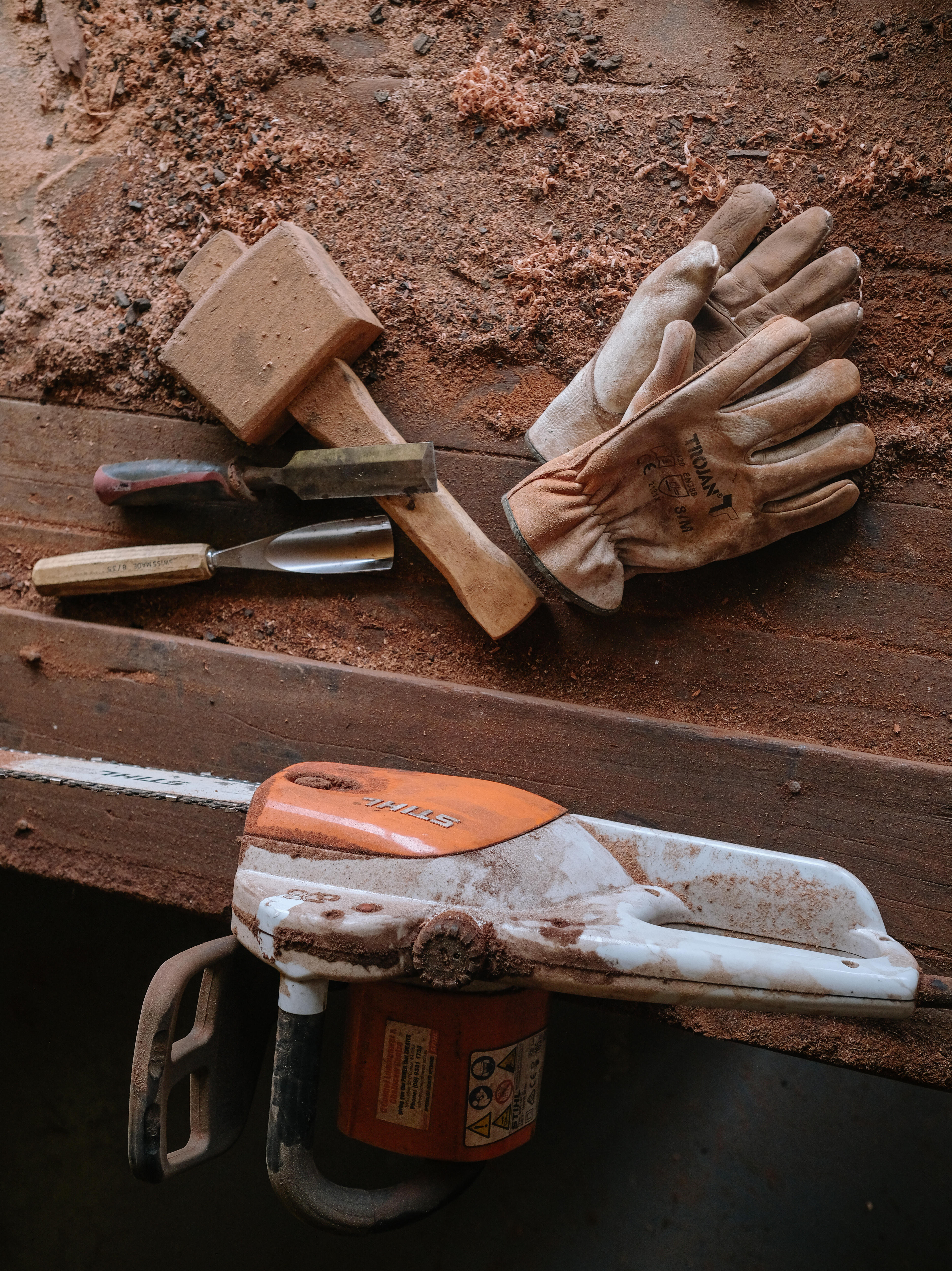 Woodworking tools on a bench, including a mallet and gloves 
