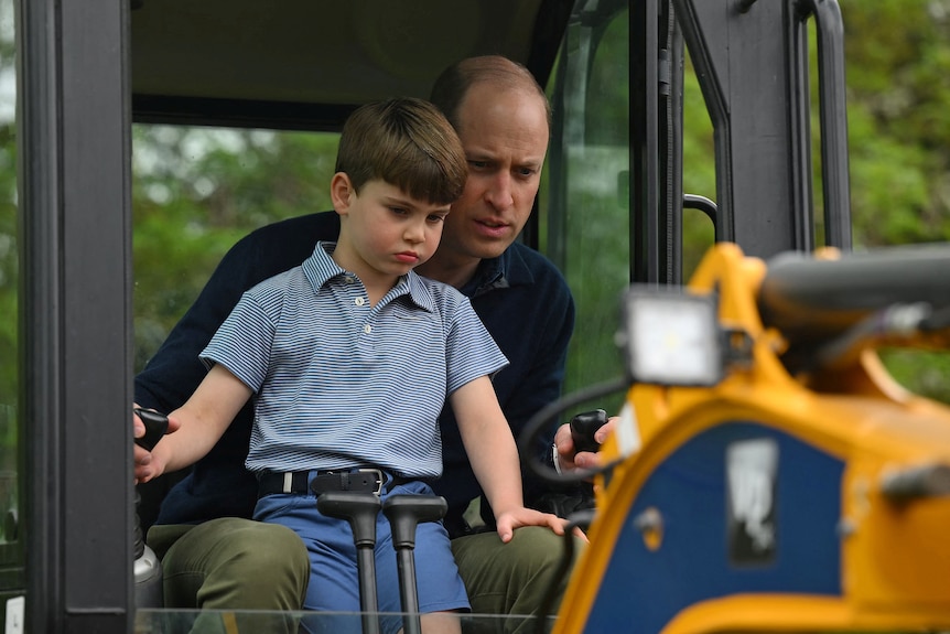 William controls a digger while Louis sits in his lap.