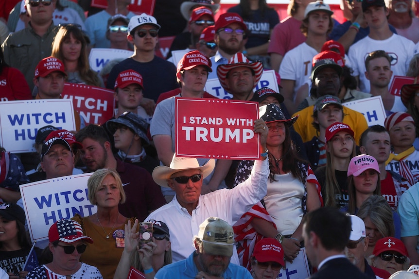 Supporters of former U.S. President Donald Trump holds signs saying "with hunt" at his first campaign rally.