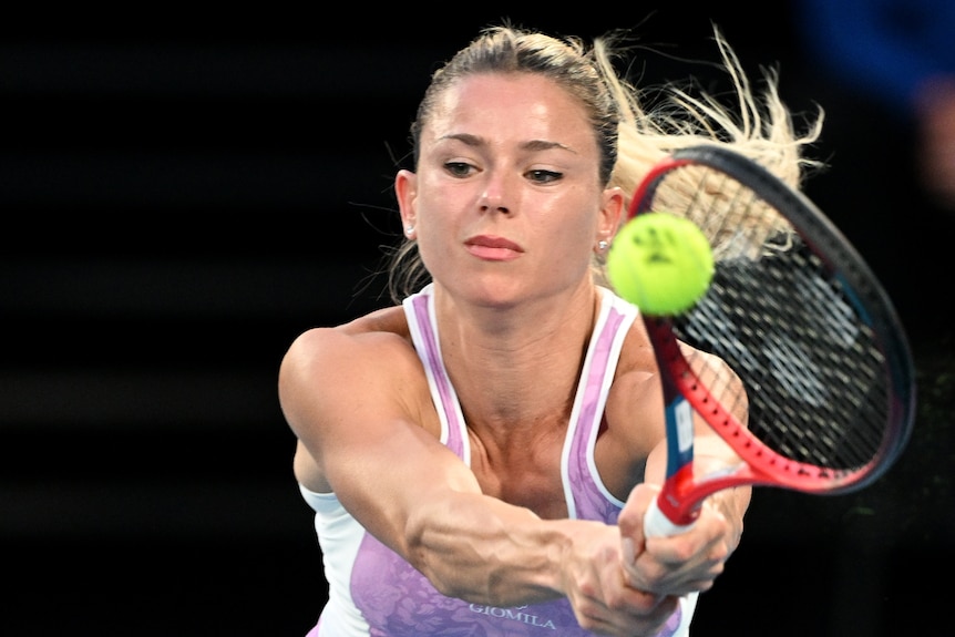 Camila Giorgi holds a racquet out to a tennis ball mid-air.