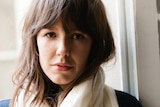 The author, a young woman with long brown hair and brown eyes, standing in front of a window.