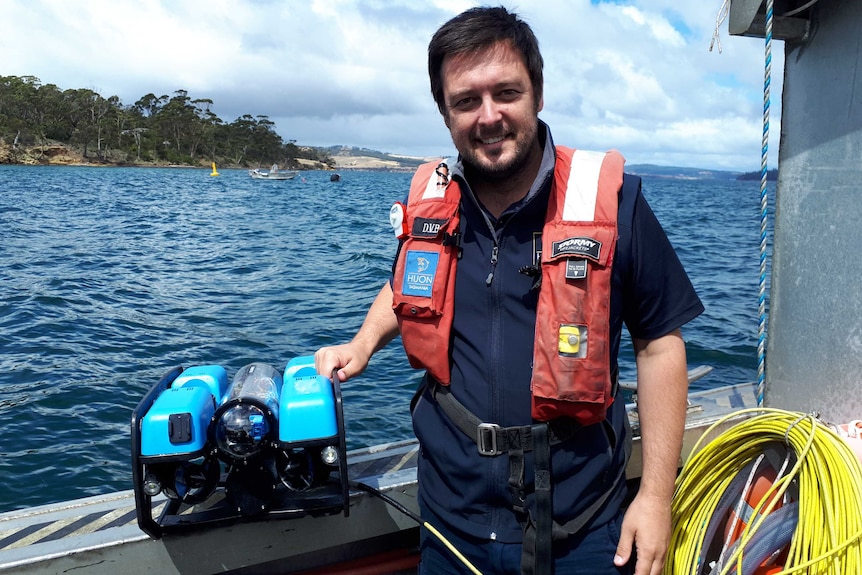 Man in life jacket stands on boat