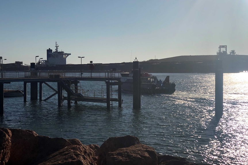 A shipping port with a gangway over the water and a small boat