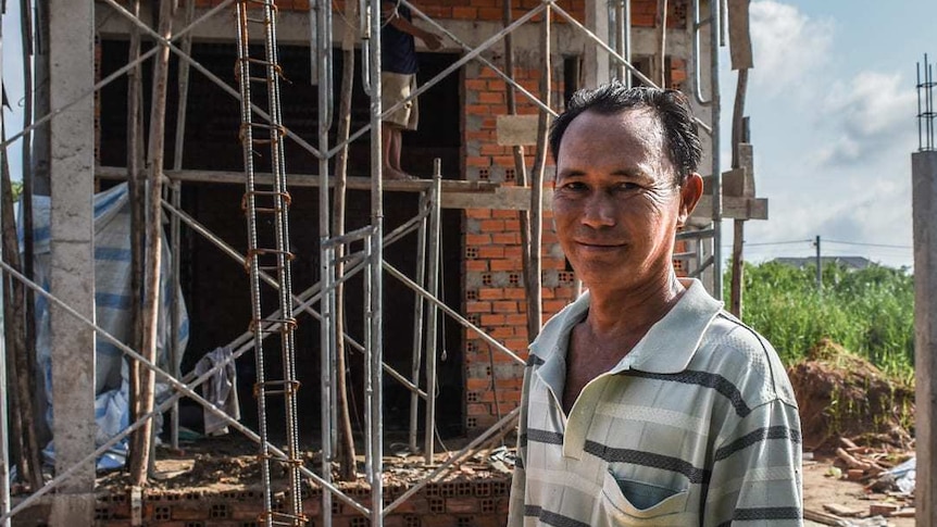 Thanh in front of a house in construction.