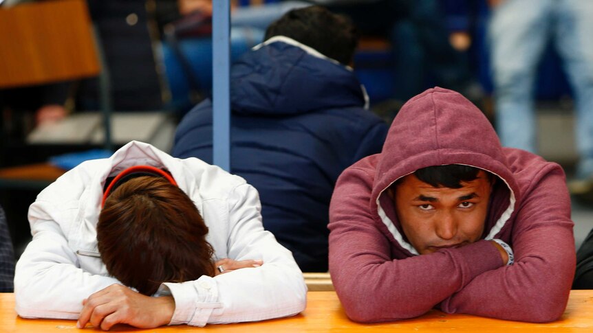 Migrants rest at a table at a registration centre in Passau, Germany