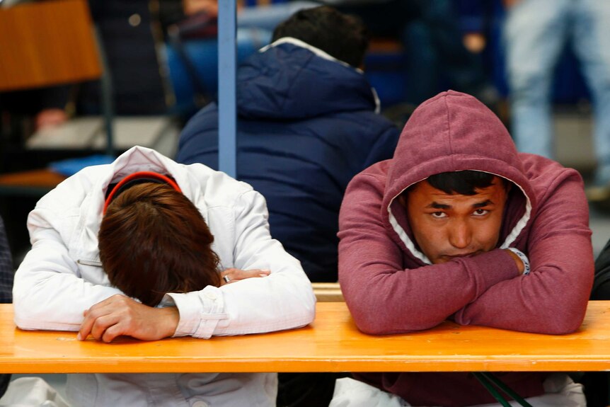 Migrants rest at a table at a registration centre in Passau, Germany